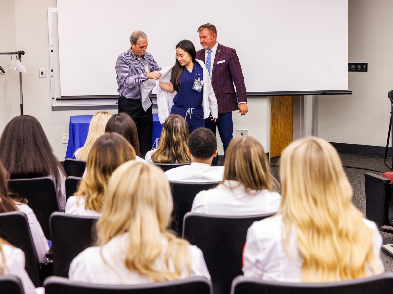 New Radiological Sciences student Michelle Zhang, receives her white coat from Dr. Lee Brown, left and SHRP Dean Jay Garner, during orientation week at the school.