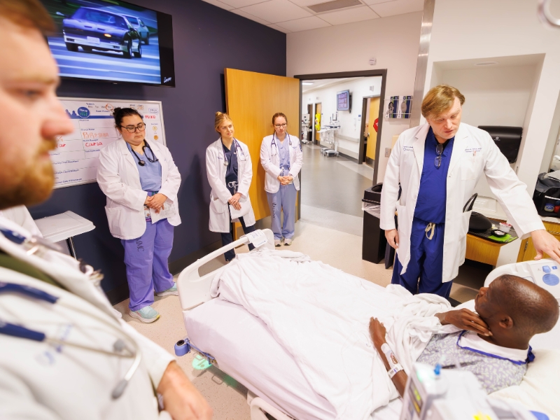 Dr. Frederick Asher, professor of medicine, talks with patient, Michael Martin, as members of his team, from left, Dr. Stephen Cole, resident; Megan Walker, medical student; Dr. Hannah Bell , resident; and Kaitlyn Barber Newbaker, medical student, look on.