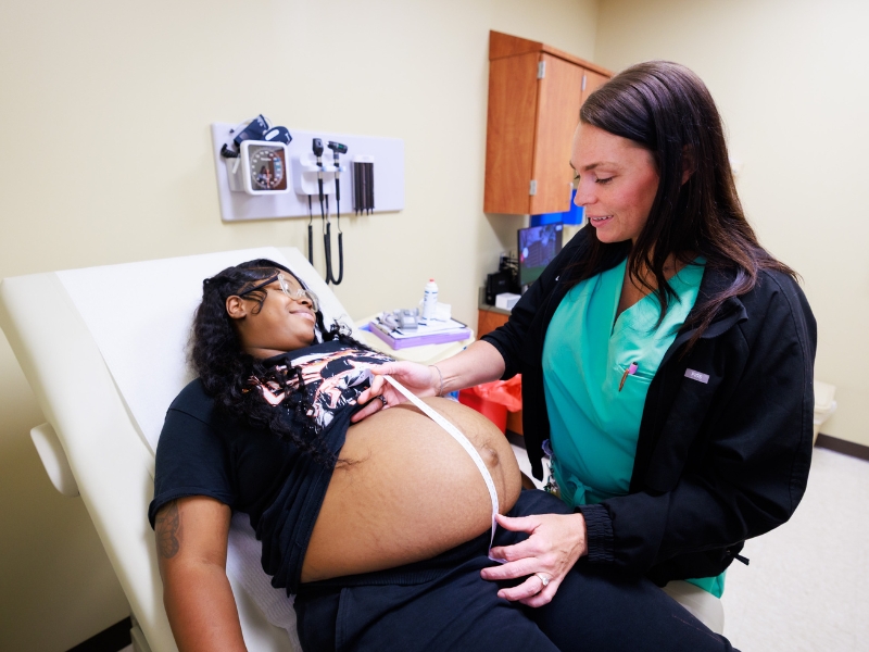 Nurse-midwife Jessica Martin measures Zeveaunna Hackett's belly to monitor the baby's growth during a prenatal appointment.