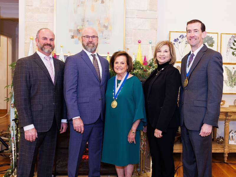 Dr. Bill Pierce's sons, Dr. Sam Pierce and Dr. Paul Pierce; his wife, Patricia Pierce, Dr. LouAnn Woodward and Dr. Calvin Thigpen pose for photo at the chair naming ceremony.