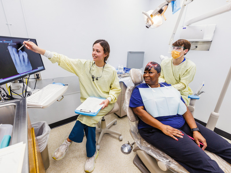 Avery Gibens, fourth-year dental student, with partner Jolan Mills, second-year dental student, walks Tenika Spann of Jackson through her upcoming procedure.