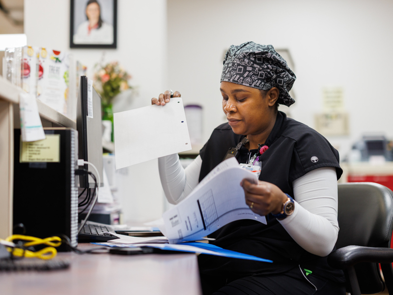 Angela Masuku, a registered nurse on 5 Wiser, charts her patient care on paper.