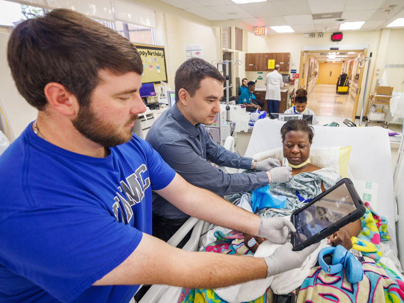 Supported by the Mississippi Center for Clinical and Translational Research, Dr. Tim Yen, assistant professor of medicine and nephrologist, second from left, and Thomas Hudson, clinical research coordinator, collect research measurements from patient April Jackson during dialysis.