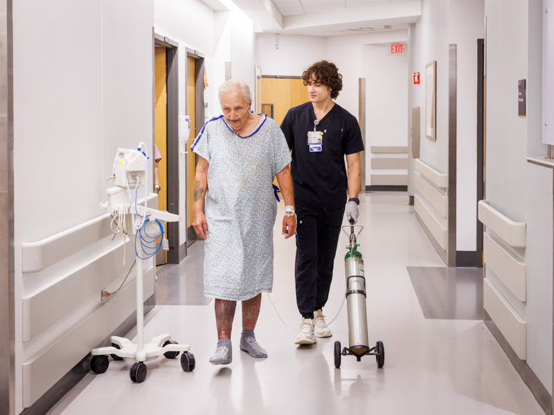John Stephen Nasekos, one of seven mobility technicians in rehabilitative services, assists patient Ernest Weathersby with his morning exercise.