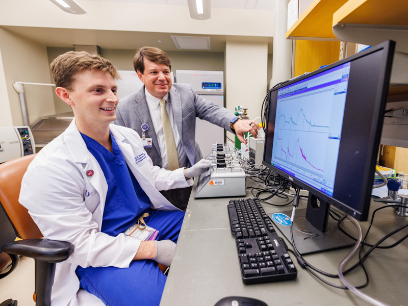 MD-PhD student Jack Berman, left, reviews research data with Dr. Lee Bidwell, associate vice chancellor for research, whose mentorship allows Berman to explore pharmacology and new therapeutics alongside his cardiovascular research.