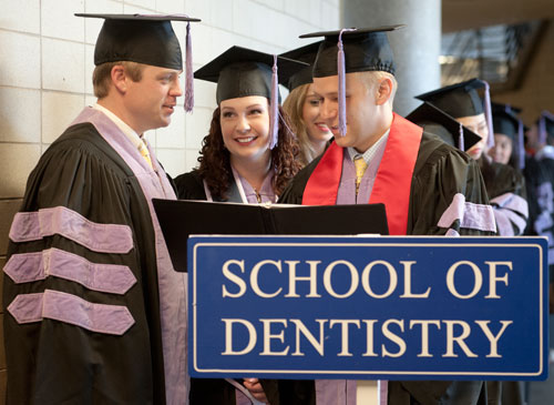 SOD graduates stand with SOD sign at graduation ceremonies
