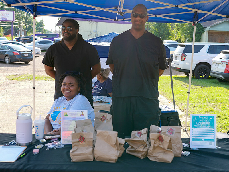 Representatives from the UMMC Express Lifestyle Clinic at an outdoor resource table under a popup tent.