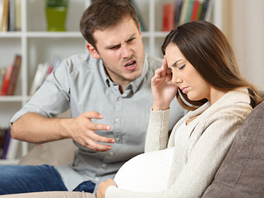 Sad pregnant woman fighting with her husband sitting on a sofa at home.