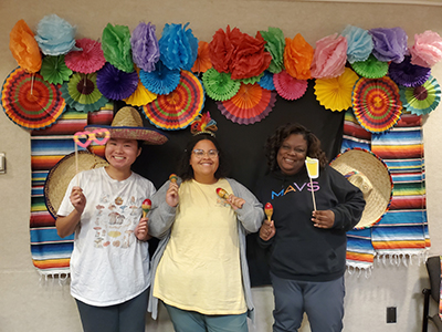 group of students holding props standing in front of a Hispanic themed photo booth