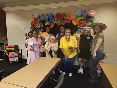 group of faculty and staff holding props standing in front of a Hispanic themed photo booth