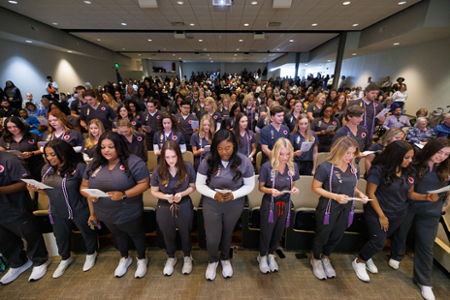 nursing students and nurses in attendance reciting the Nightingale Pledge during a Pinning ceremony