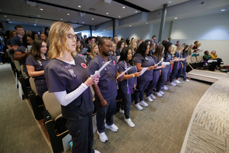 nursing students and nurses in attendance reciting the Nightingale Pledge during a Pinning ceremony